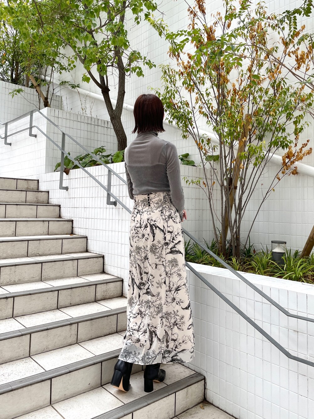 グレー系のTシャツ/カットソー、ホワイト系のスカート、ブラック系のブーツを着用したレディースの秋コーディネートの4枚目の写真