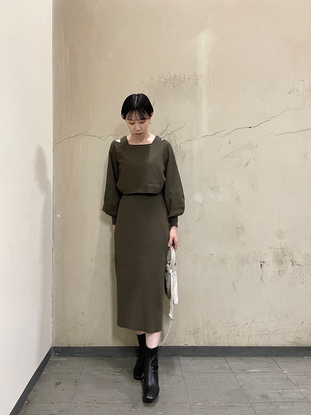 ブラウン系のワンピース、ブラック系のブーツ、ホワイト系のハンドバッグを着用したレディースの秋コーディネートの2枚目の写真