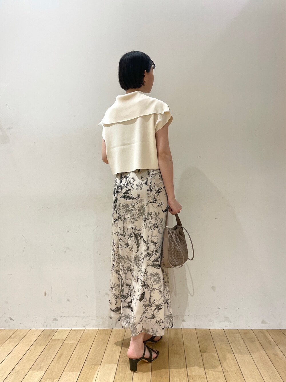 ホワイト系のニット/セーター、ホワイト系のスカート、ブラウン系のハンドバッグを着用したレディースの春コーディネートの3枚目の写真