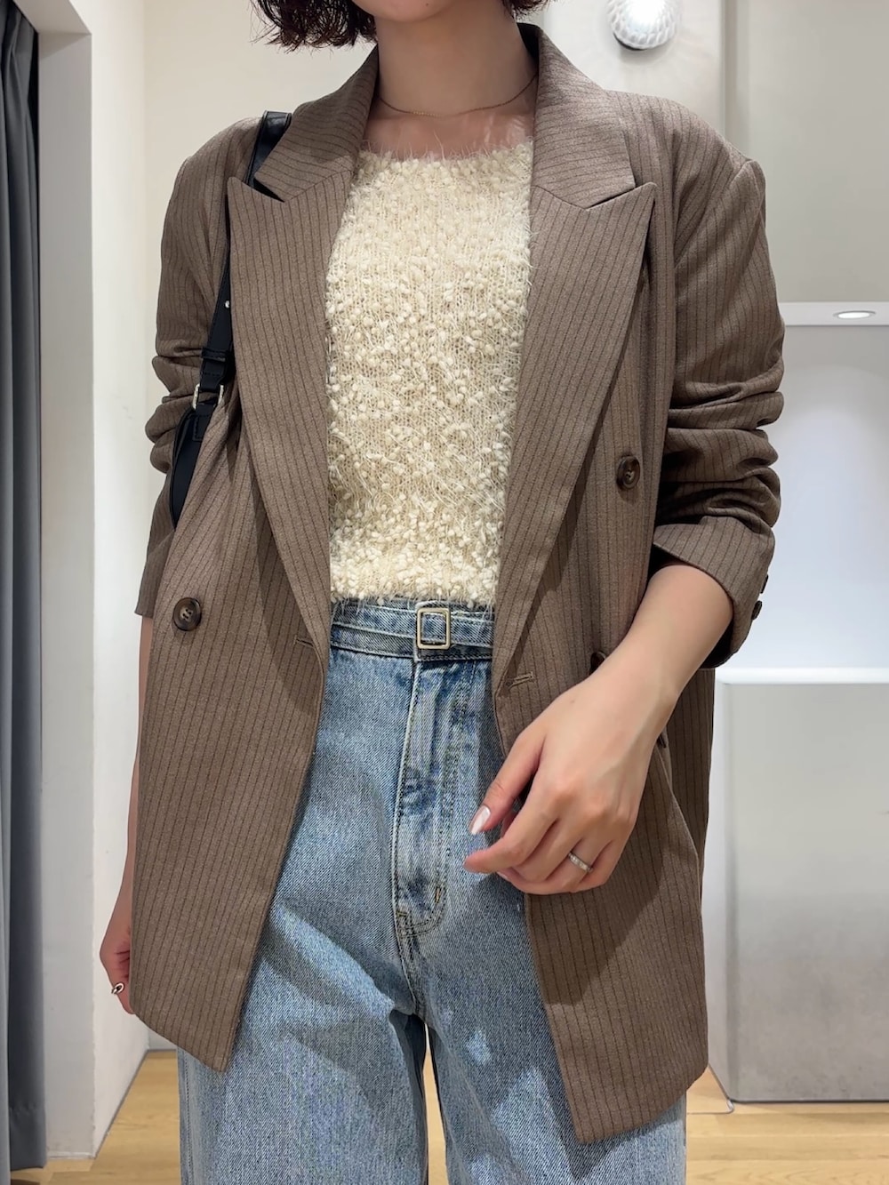 ホワイト系のニット/セーター、ブルー系のデニムパンツ、ブラック系のブーツを着用したレディースの秋コーディネートの6枚目の写真