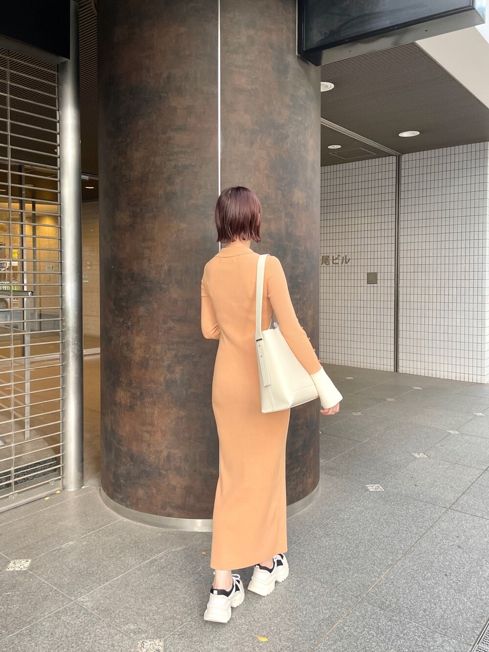 オレンジ系のワンピース、ホワイト系のショルダーバッグ、ブラック系のスニーカーを着用したレディースの冬コーディネートの4枚目の写真