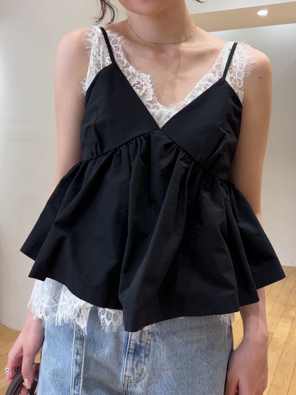 ブラック系のキャミソール、ブルー系のデニムパンツ、ブラウン系のハンドバッグを着用したレディースの夏コーディネートの5枚目の写真