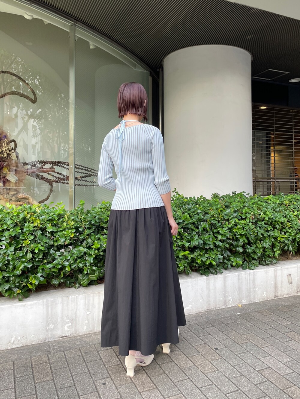 ブラック系のスカート、ブルー系のニット/セーター、ホワイト系のパンプスを着用したレディースの春コーディネートの4枚目の写真