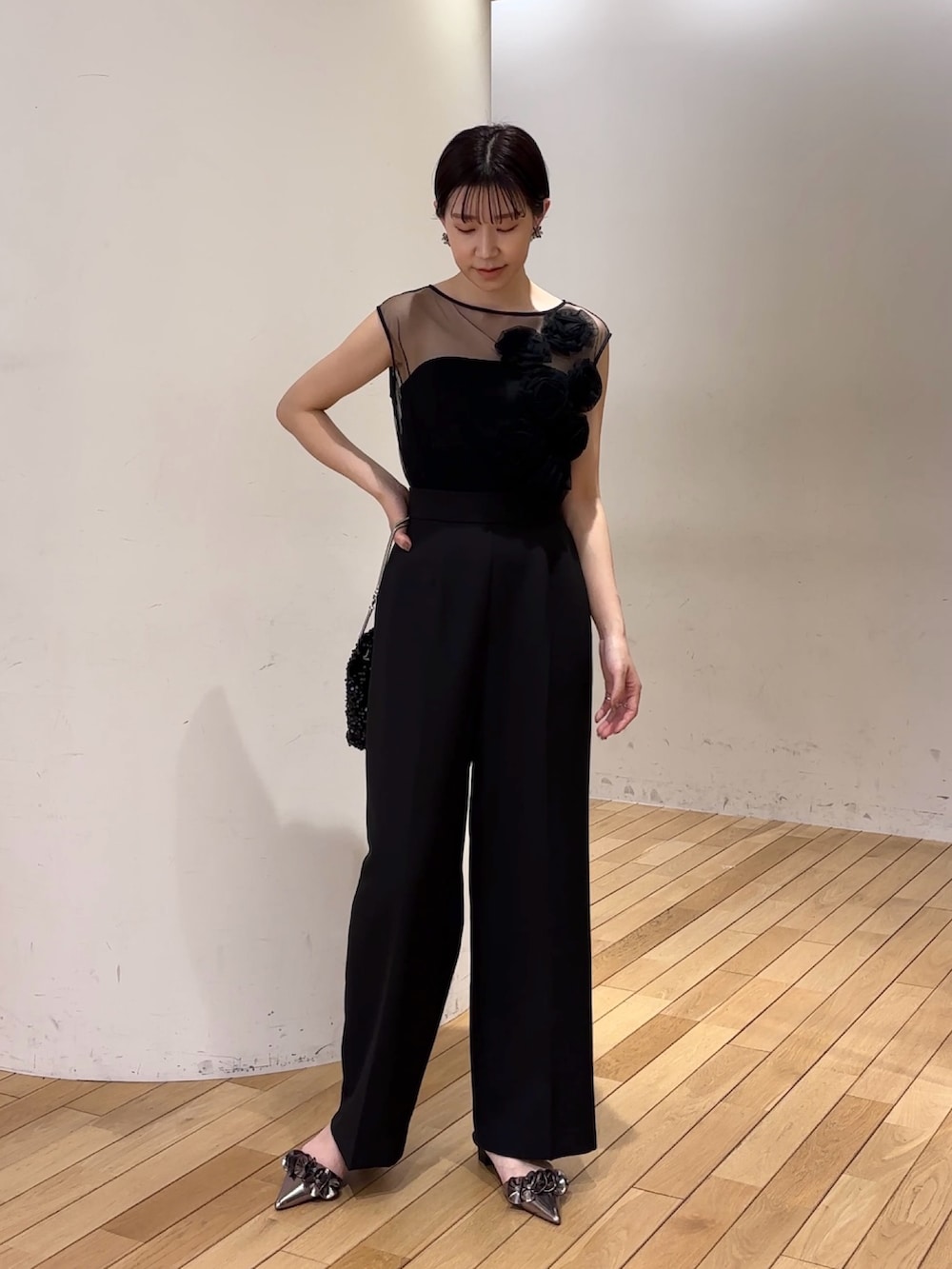 ブラック系のパンツドレス、ブラック系のショルダーバッグ、その他のパンプスを着用したレディースの春コーディネートの2枚目の写真