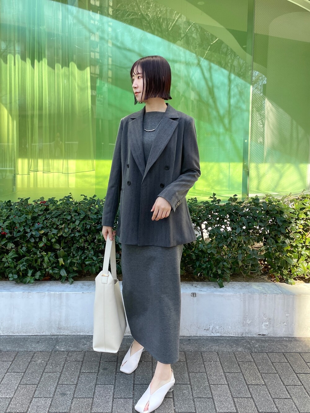 ホワイト系のパンプス、ホワイト系のショルダーバッグ、グレー系のワンピースを着用したレディースの冬コーディネートの2枚目の写真