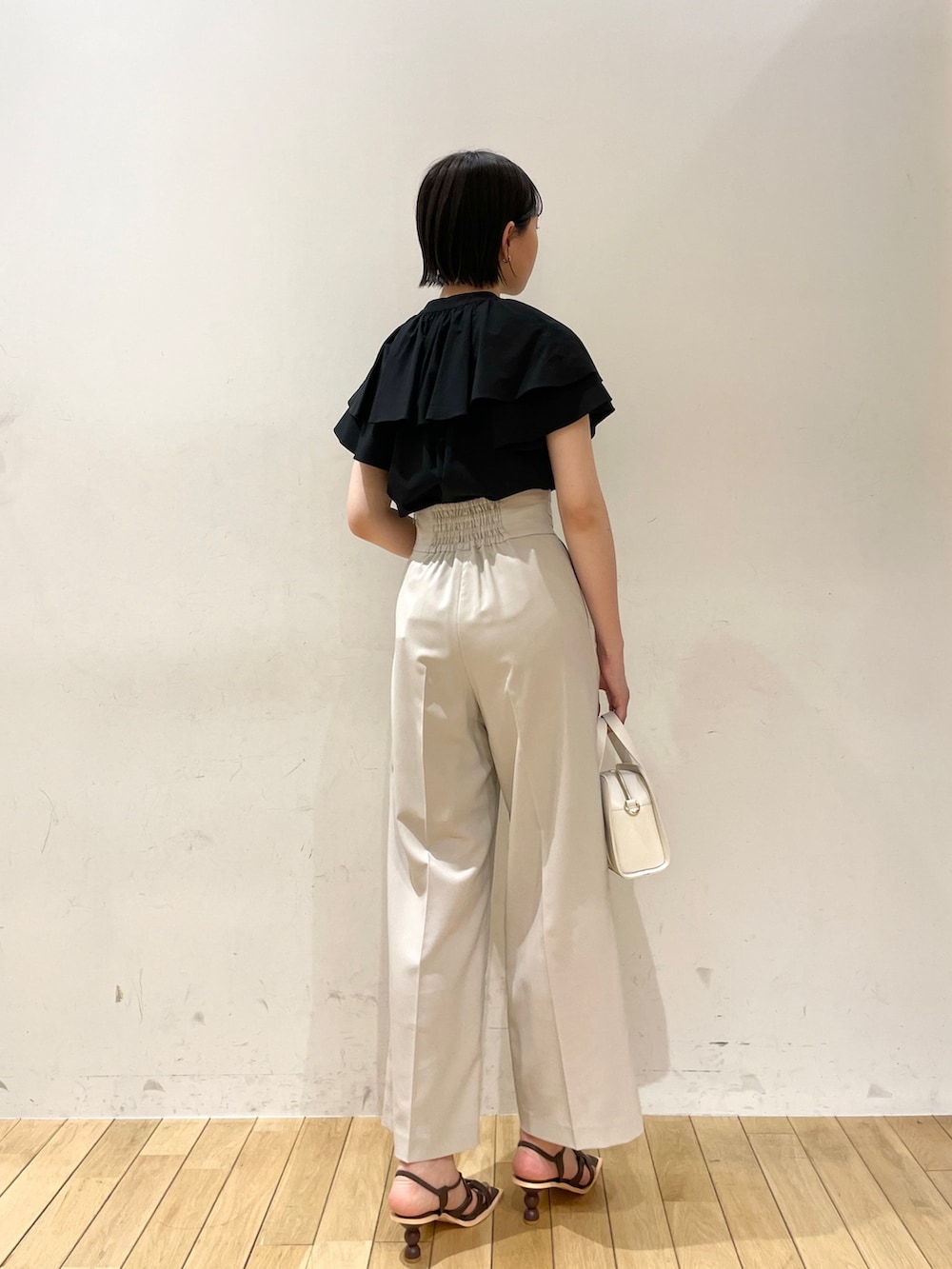 ブラック系のシャツ/ブラウス、ホワイト系のスラックス、ホワイト系のショルダーバッグを着用したレディースの夏コーディネートの4枚目の写真