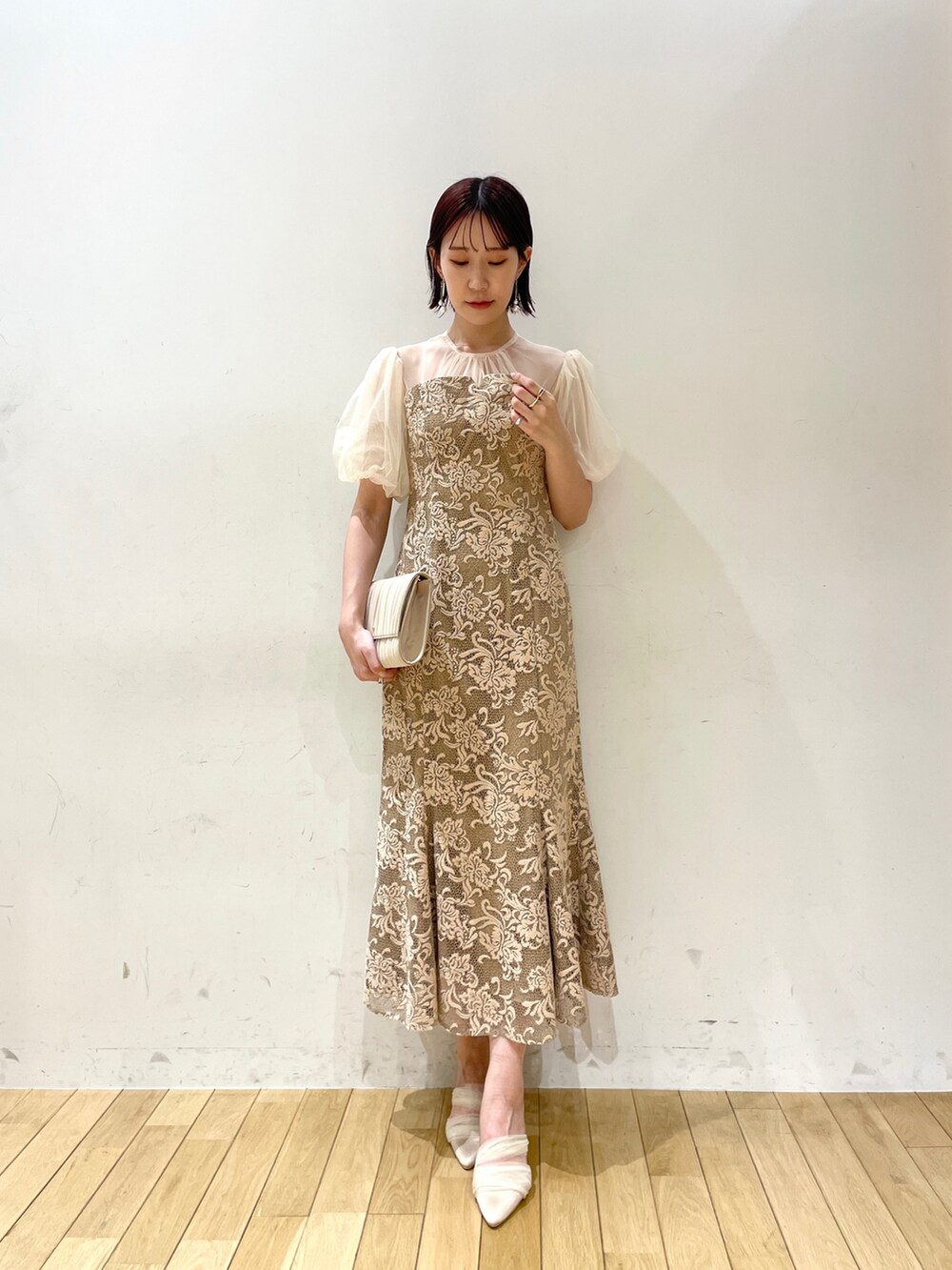 ベージュ系のハンドバッグ、ベージュ系のパンプス、ベージュ系のドレスを着用したレディースの秋コーディネートの3枚目の写真