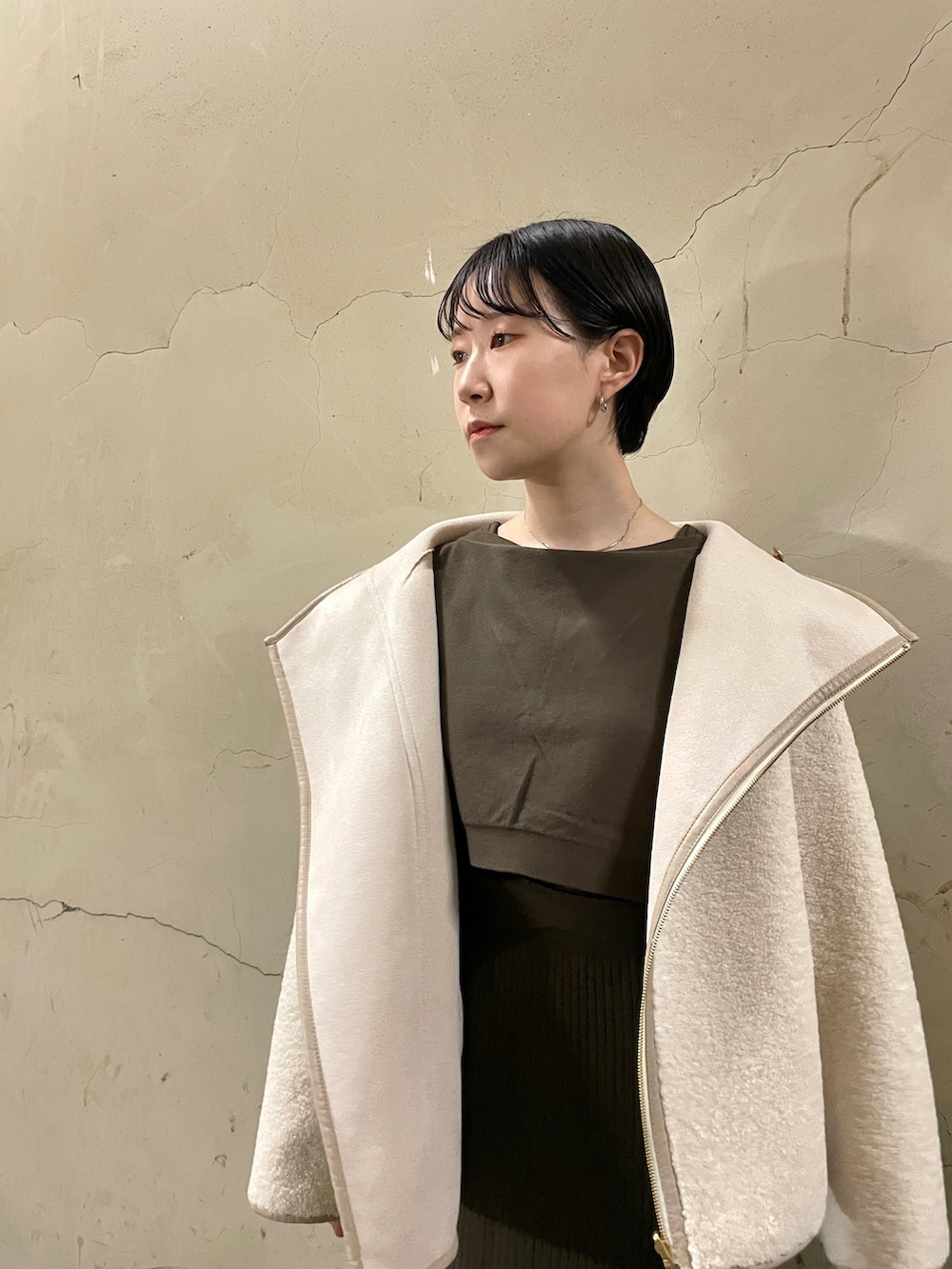 ホワイト系のブルゾン、ブラック系のブーツ、ブラウン系のワンピースを着用したレディースの秋コーディネートの4枚目の写真