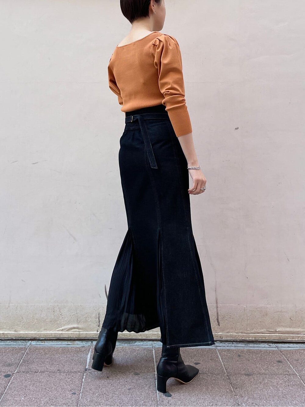 ブラック系のその他シューズ、オレンジ系のニット/セーター、ブラック系のスカートを着用したレディースの冬コーディネートの5枚目の写真