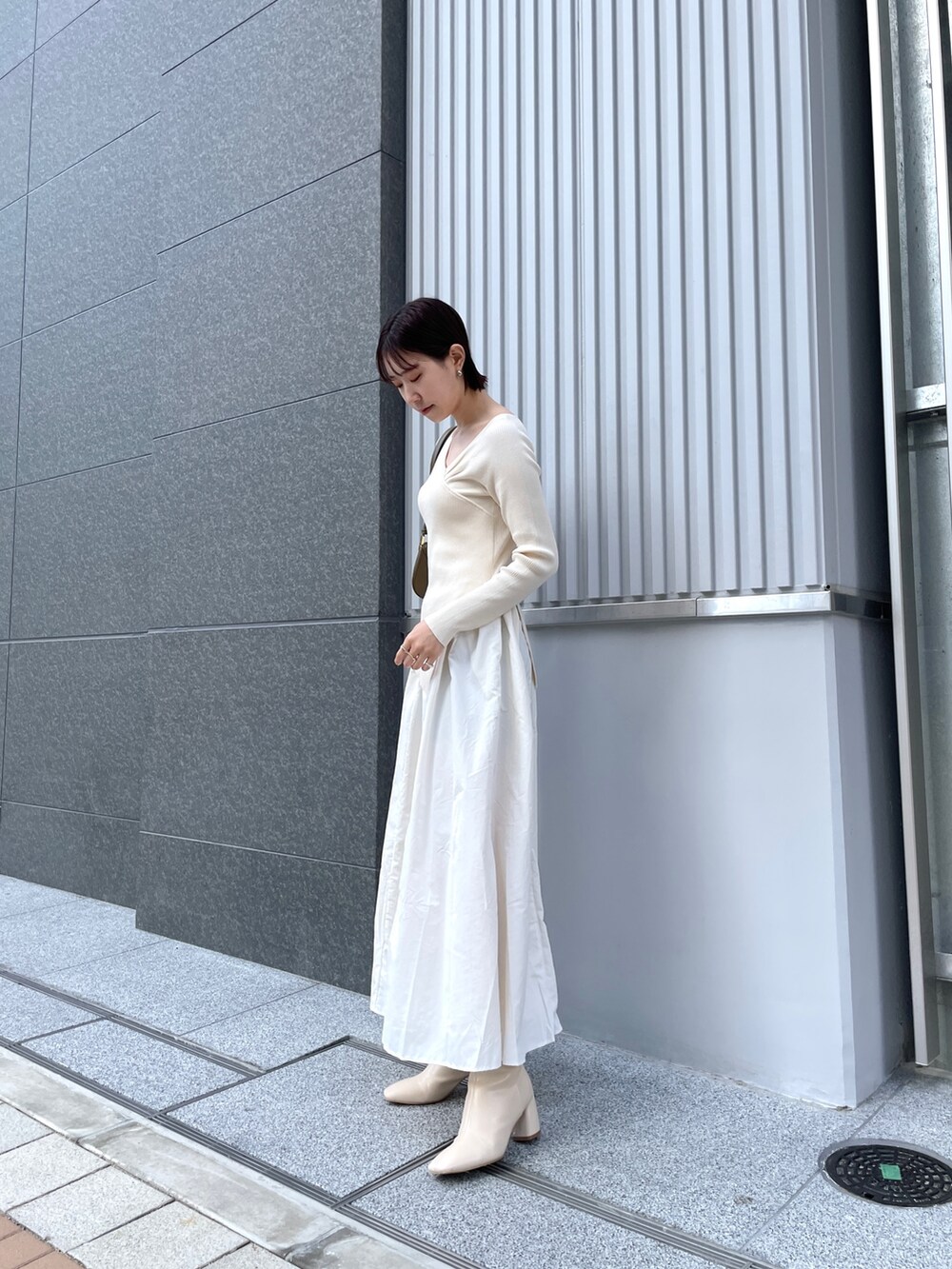 ブラウン系のショルダーバッグ、ホワイト系のブーツ、ホワイト系のワンピースを着用したレディースの春コーディネートの3枚目の写真