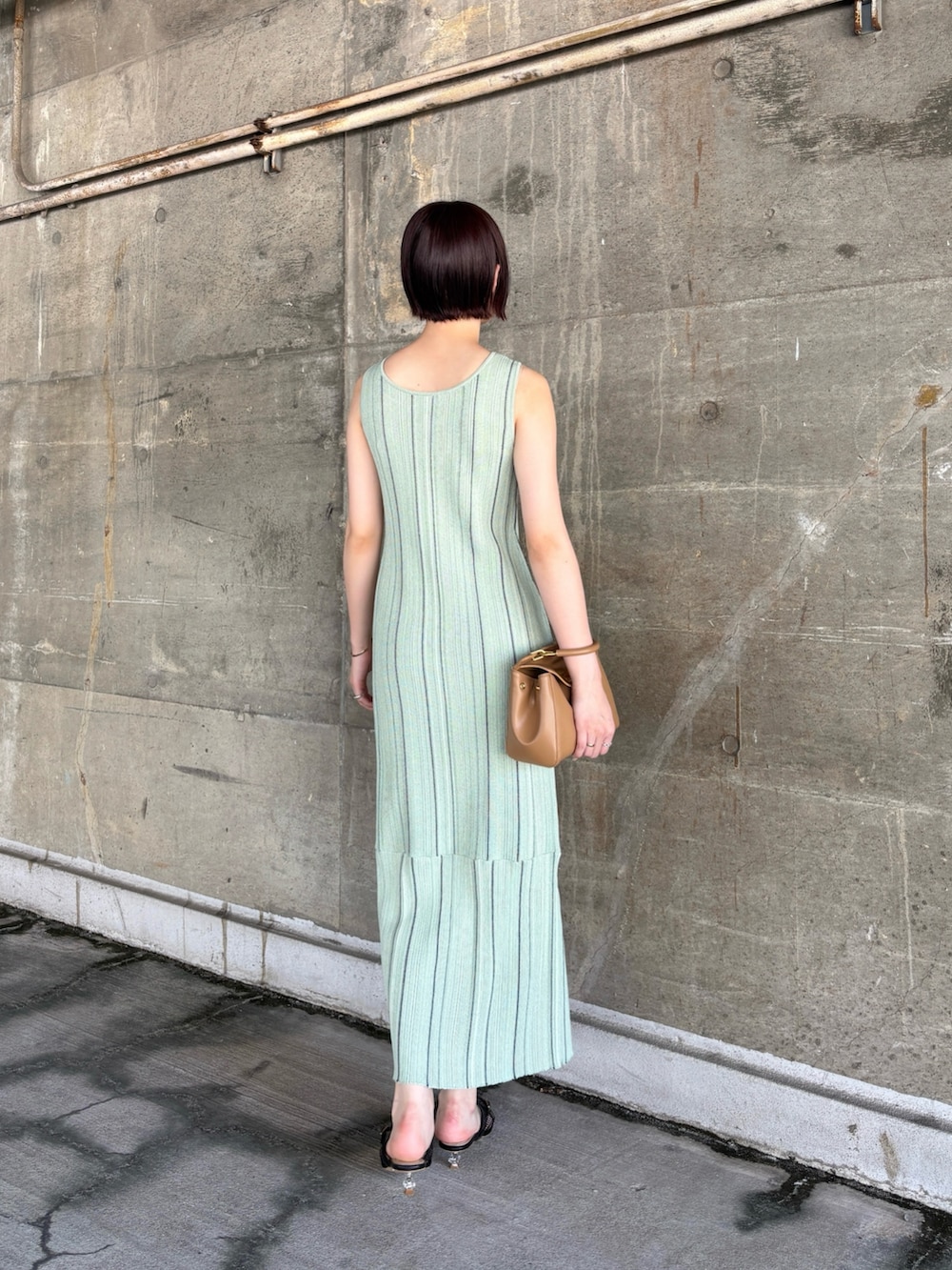 グリーン系のワンピース、ブラック系のサンダル、イエロー系のハンドバッグを着用したレディースの春コーディネートの4枚目の写真