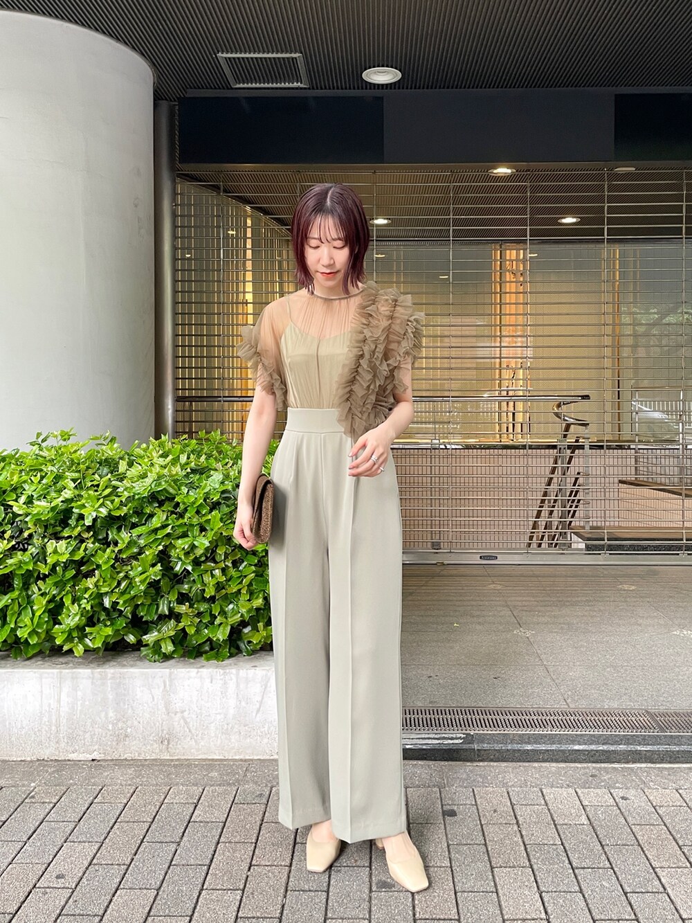 グリーン系のパンツドレス、ベージュ系のパンプスを着用したレディースの春コーディネートの3枚目の写真