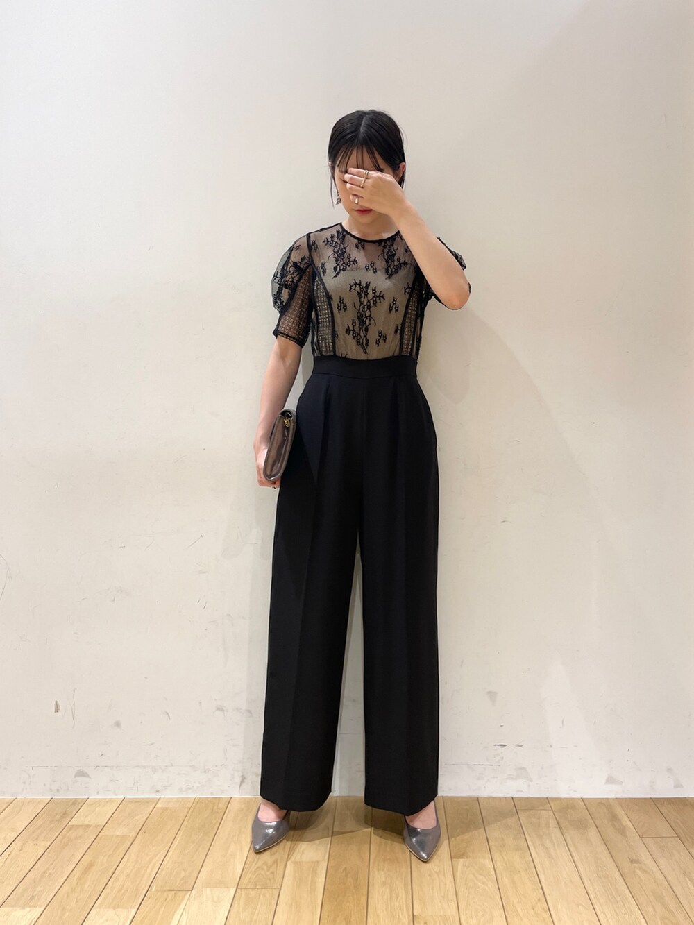 シルバー系のハンドバッグ、シルバー系のパンプス、ブラック系のパンツドレスを着用したレディースの夏コーディネートの3枚目の写真