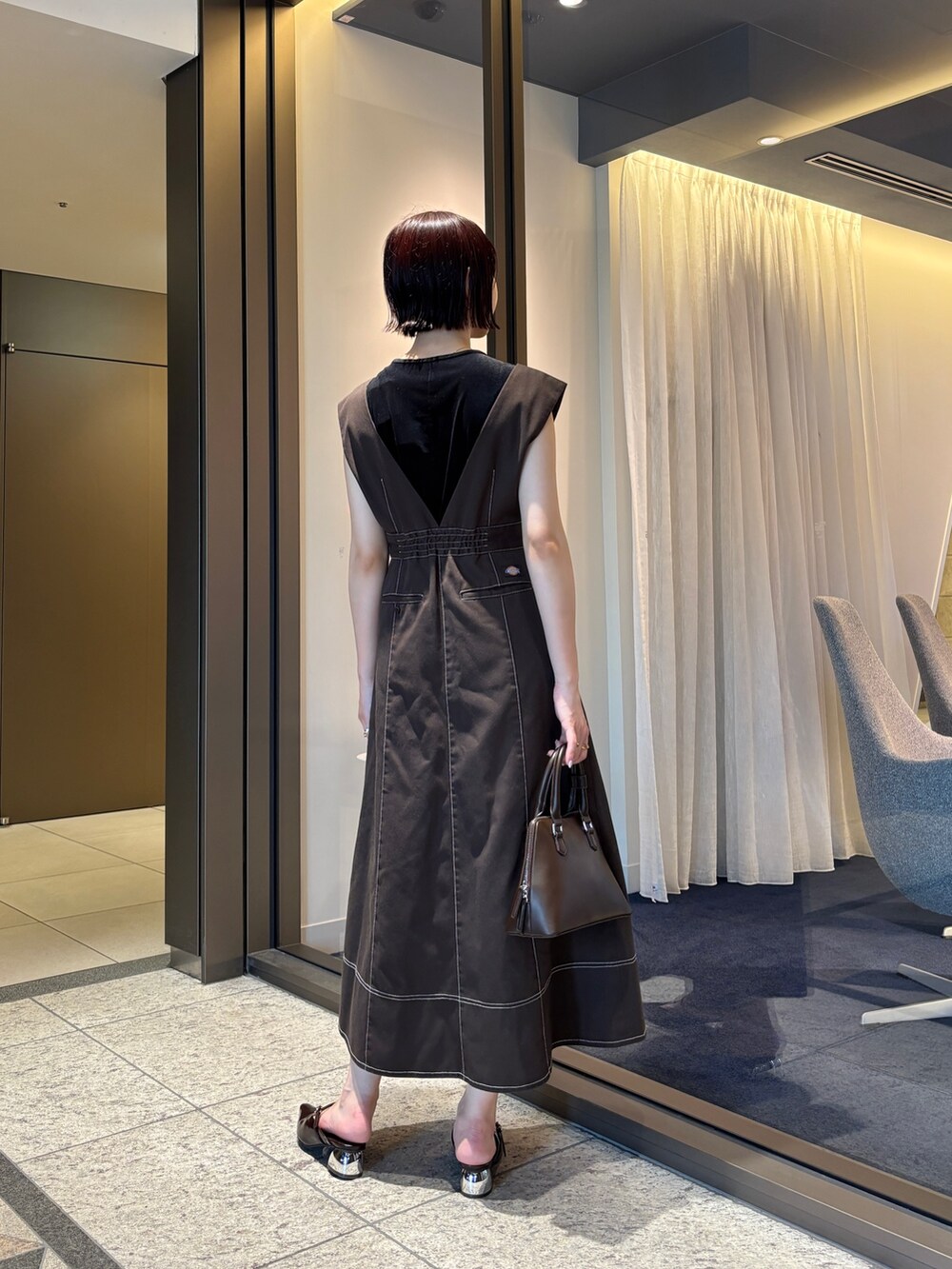 ブラウン系のジャンパースカート、ブラウン系のパンプス、ブラウン系のボストンバッグを着用したレディースの夏コーディネートの4枚目の写真