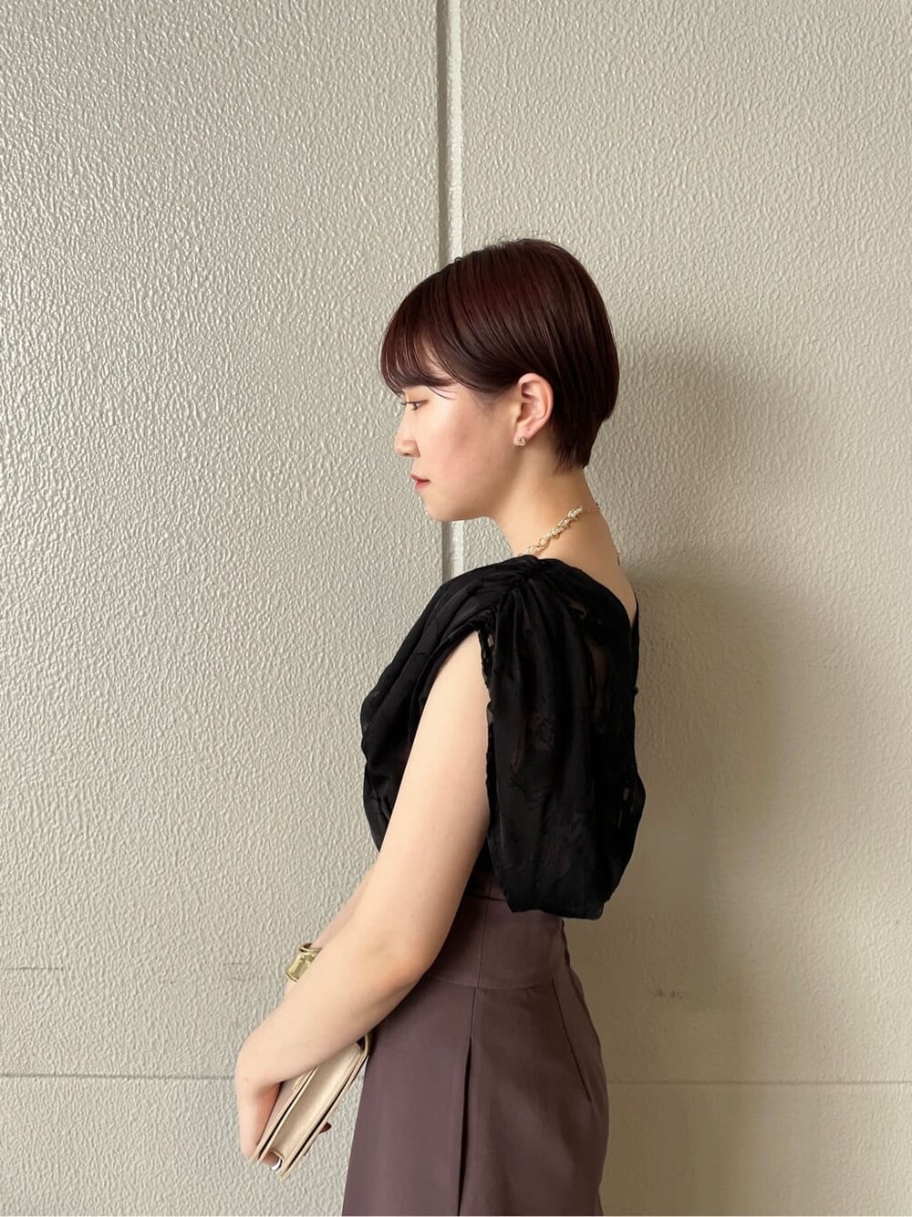パープル系のパンツドレス、シルバー系のパンプス、ベージュ系のクラッチバッグを着用したレディースの春コーディネートの8枚目の写真