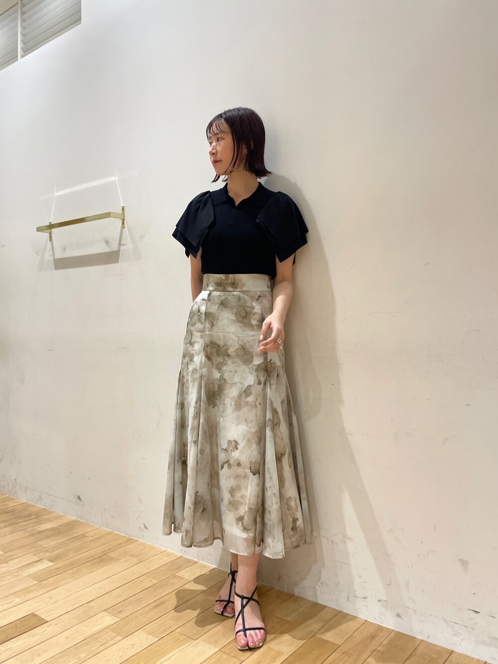 ブラック系のサンダル、グレー系のスカート、ブラック系のニット/セーターを着用したレディースの夏コーディネートの2枚目の写真