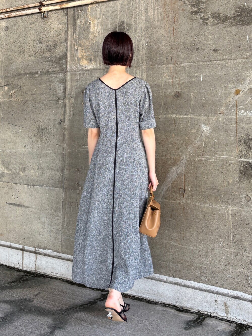 ブラック系のワンピース、イエロー系のハンドバッグ、ブラック系のサンダルを着用したレディースの夏コーディネートの4枚目の写真