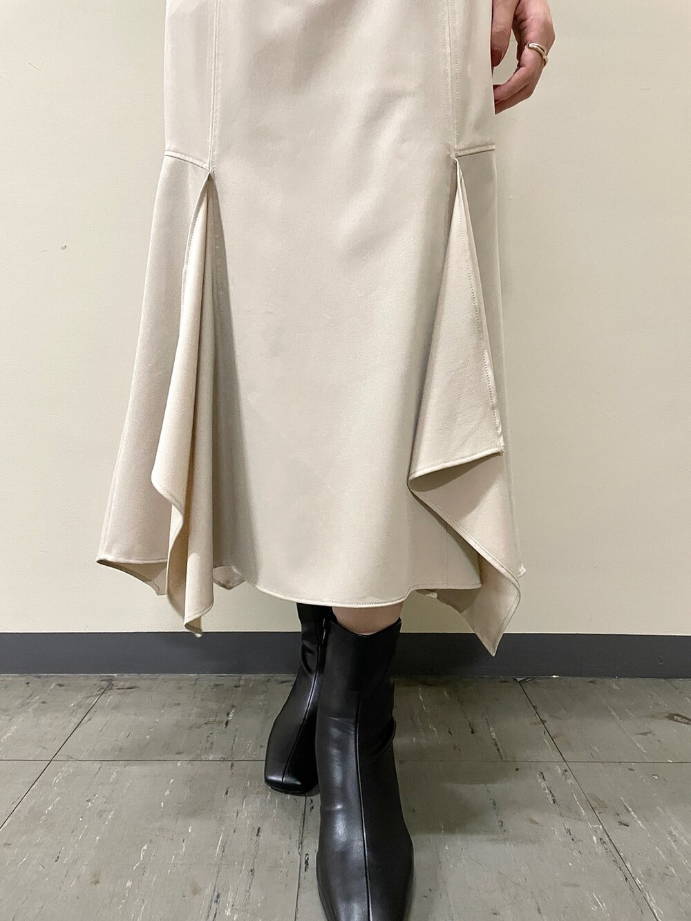 ベージュ系のスカート、ブラック系のニット/セーター、ブラック系のブーツを着用したレディースの秋コーディネートの9枚目の写真