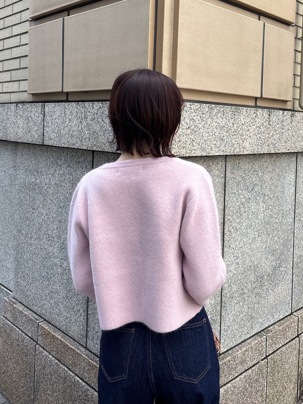 ブルー系のデニムパンツ、ピンク系のテーラードジャケット、イエロー系のハンドバッグを着用したレディースの冬コーディネートの5枚目の写真