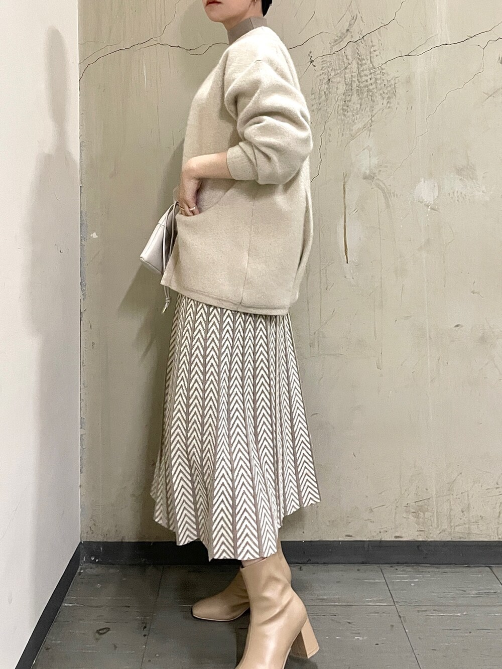 ホワイト系のカーディガン/ボレロ、ベージュ系のブーツ、ホワイト系のハンドバッグを着用したレディースの冬コーディネートの4枚目の写真