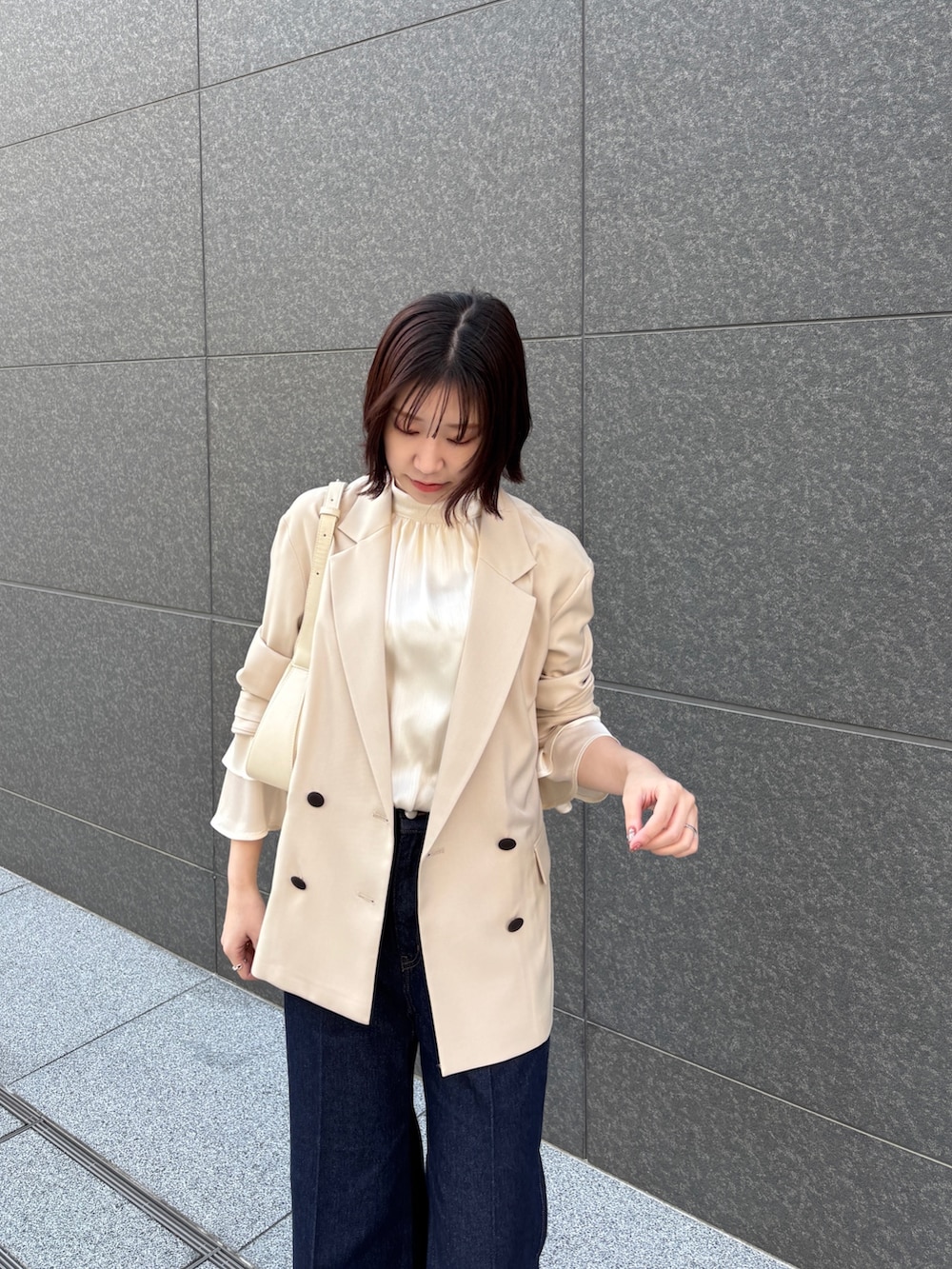 ホワイト系のシャツ/ブラウス、ホワイト系のハンドバッグ、ベージュ系のテーラードジャケットを着用したレディースの春コーディネートの3枚目の写真