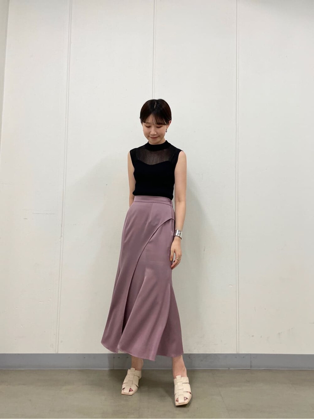 ピンク系のスカート、ホワイト系のサンダル、ブラック系のニット/セーターを着用したレディースの夏コーディネートの2枚目の写真