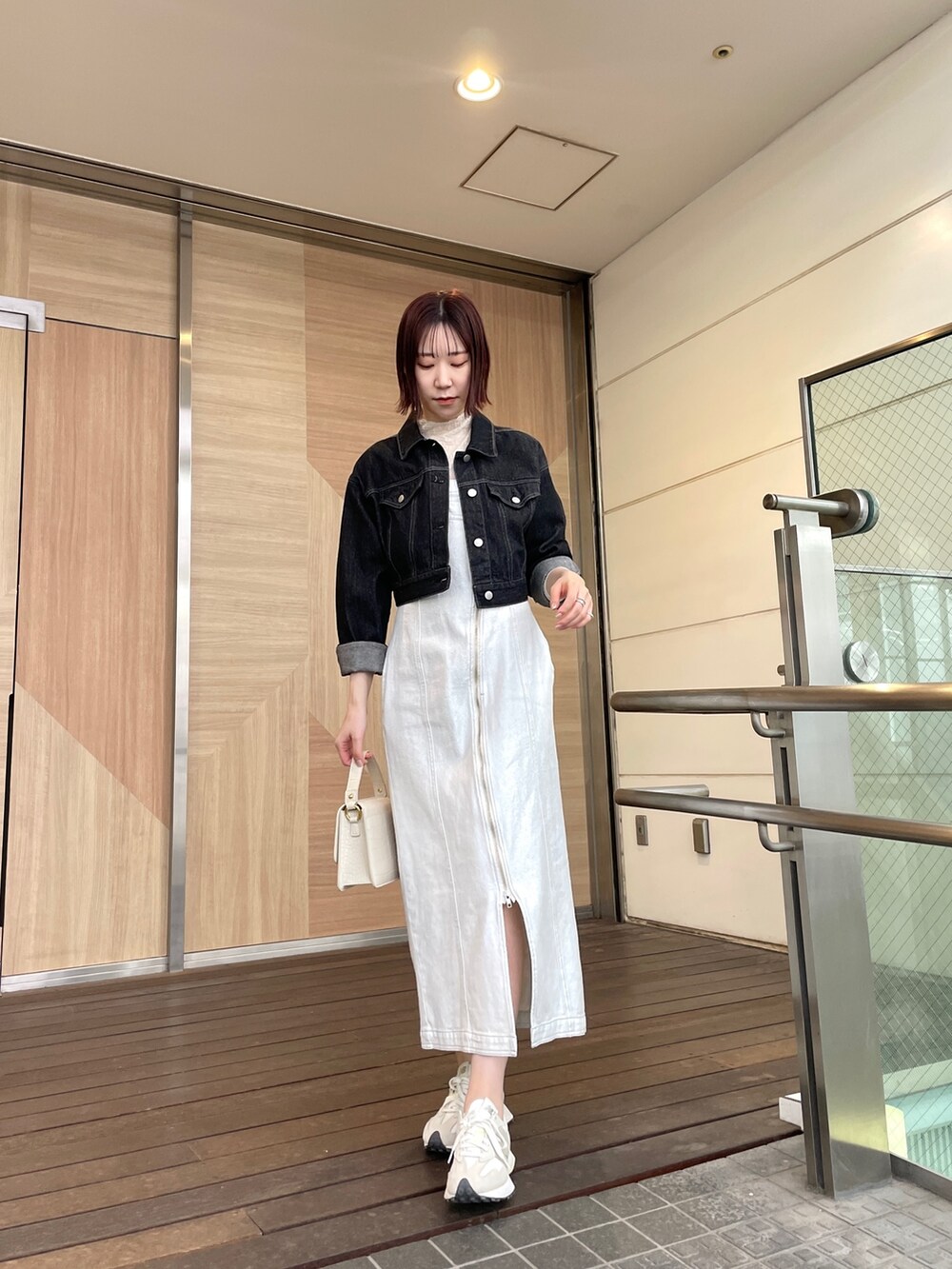 ホワイト系のショルダーバッグ、ホワイト系のワンピース、ブラック系のデニムジャケットを着用したレディースの春コーディネートの5枚目の写真