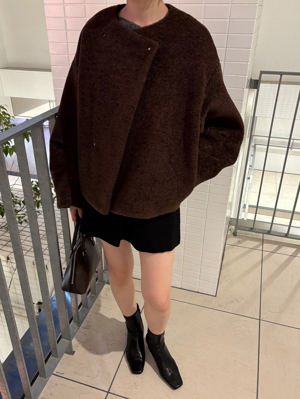 グレー系のニット/セーター、ブラウン系のブルゾン、ブラウン系のボストンバッグを着用したレディースの秋コーディネートの5枚目の写真