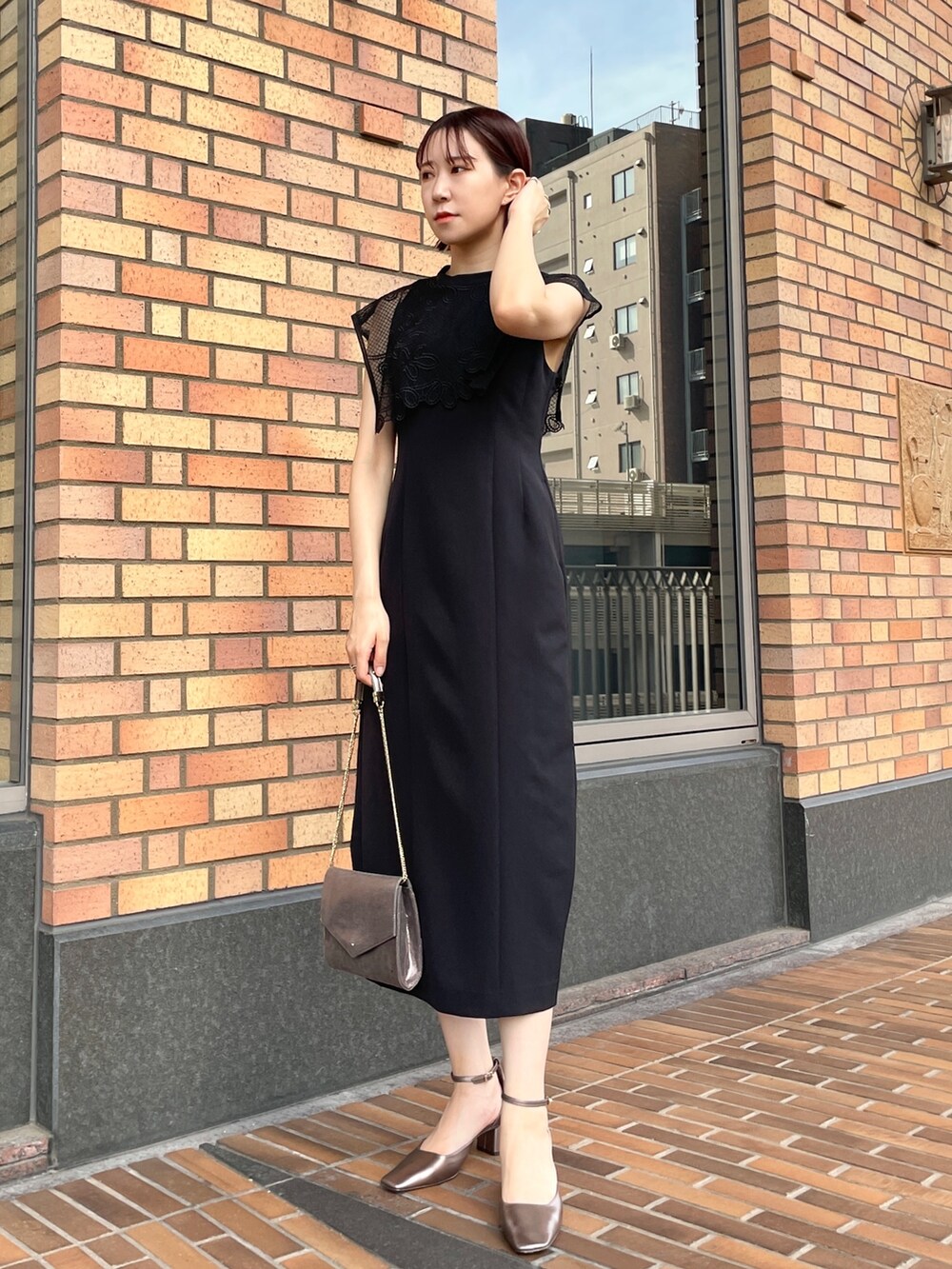 グレー系のノーカラーコート、ブラック系のドレス、シルバー系のハンドバッグを着用したレディースの秋コーディネートの7枚目の写真