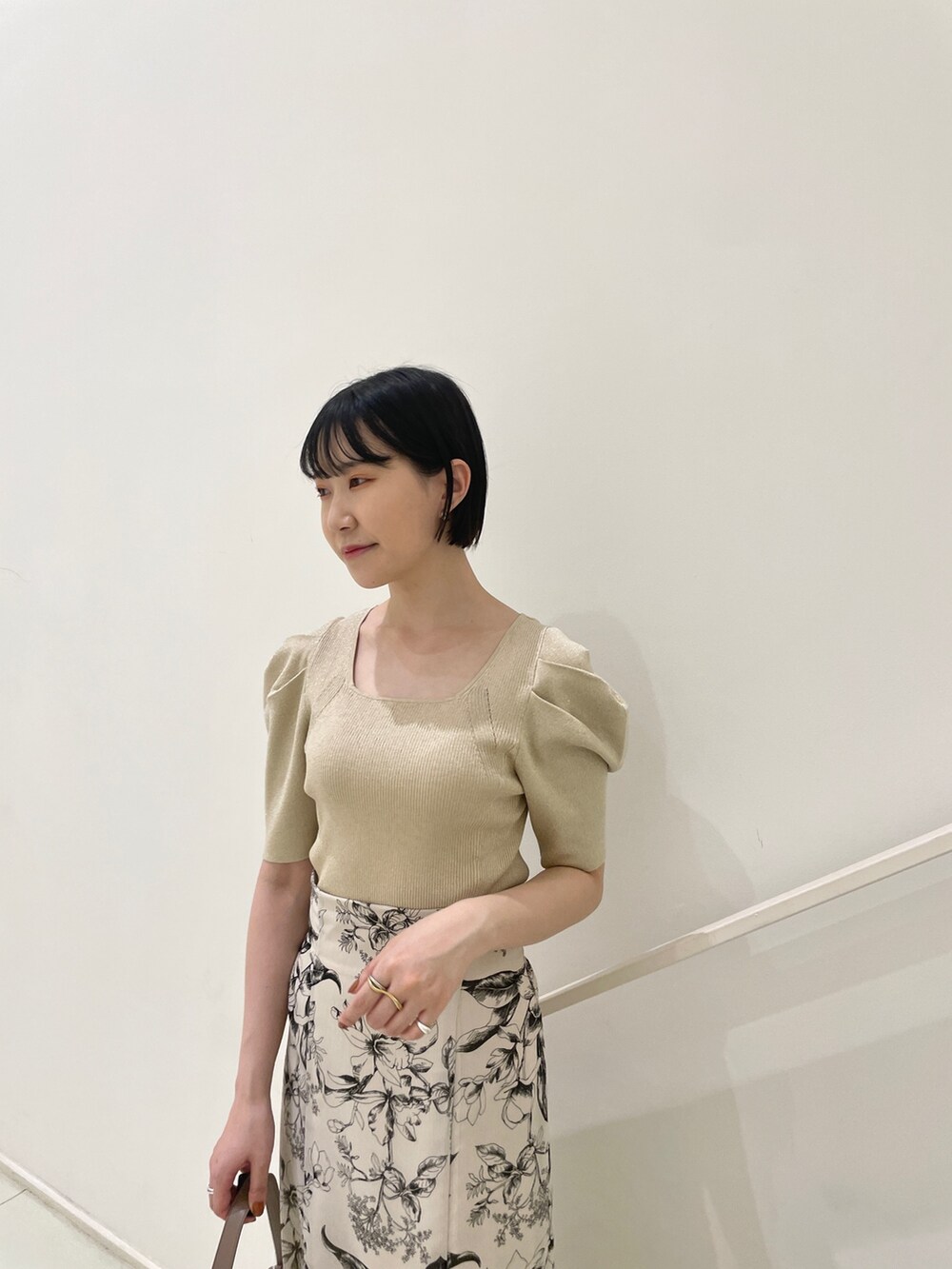 ホワイト系のスカート、ベージュ系のニット/セーター、ブラウン系のハンドバッグを着用したレディースの春コーディネートの5枚目の写真