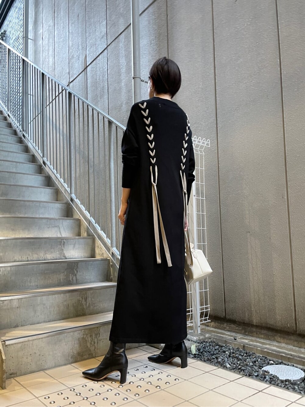 ブラック系のその他シューズ、ホワイト系のハンドバッグ、ブラック系のワンピースを着用したレディースの冬コーディネートの4枚目の写真