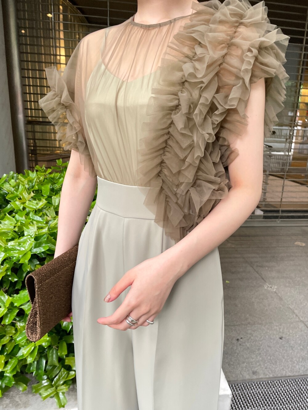 グリーン系のパンツドレス、ベージュ系のパンプスを着用したレディースの春コーディネートの7枚目の写真