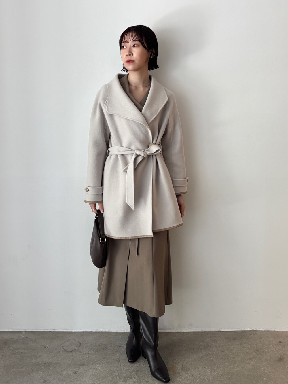 ホワイト系のワンピース、ブラウン系のハンドバッグ、ブラウン系のブーツを着用したレディースの秋コーディネートの8枚目の写真