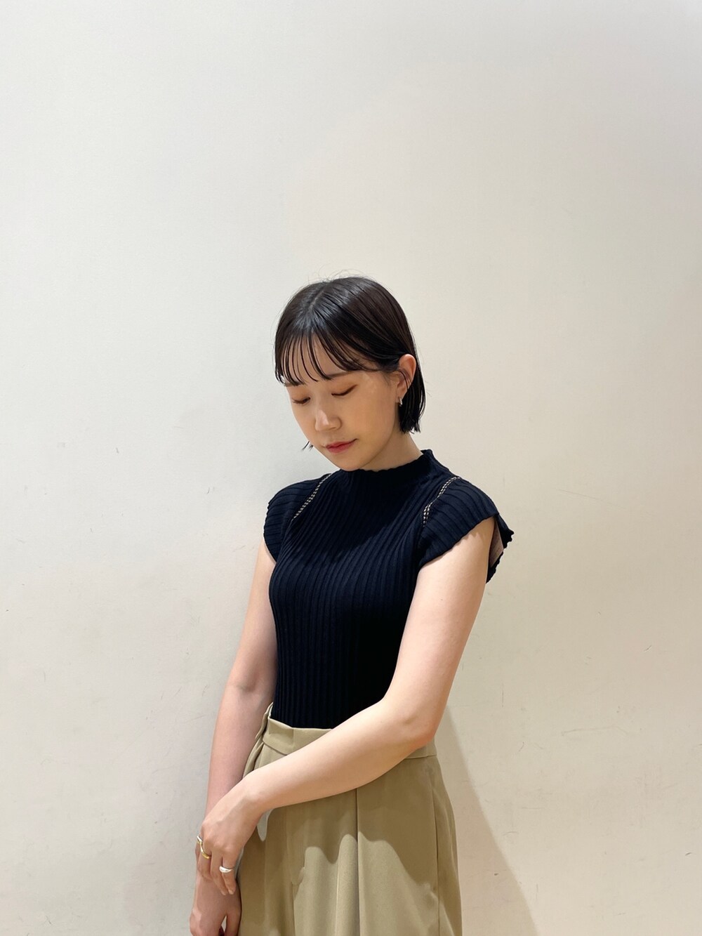 ブラック系のニット/セーター、ベージュ系のスラックス、ホワイト系のハンドバッグを着用したレディースの夏コーディネートの5枚目の写真