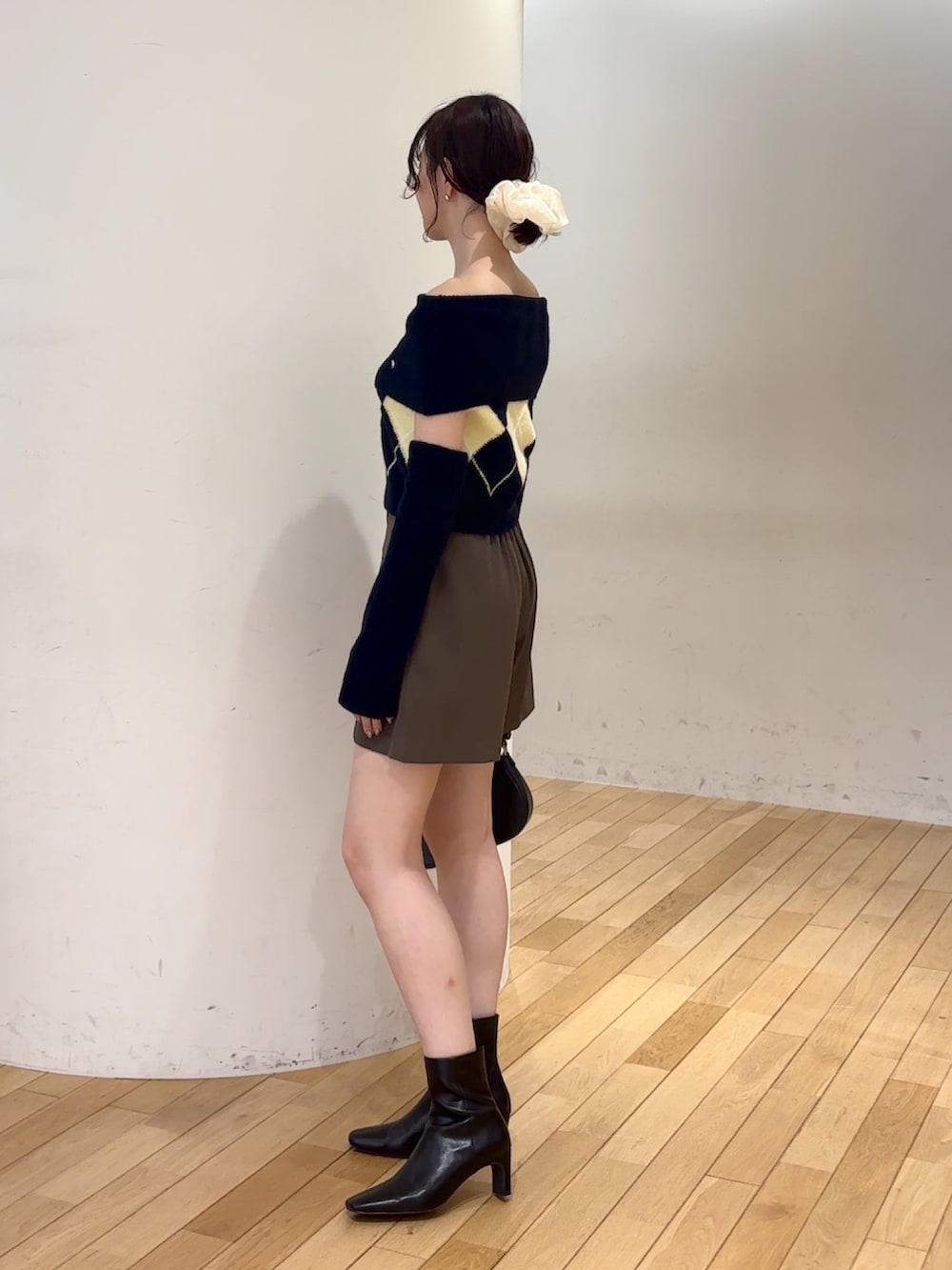 ブラウン系のその他パンツ、ブルー系のニット/セーター、ブラック系のハンドバッグを着用したレディースの夏コーディネートの2枚目の写真