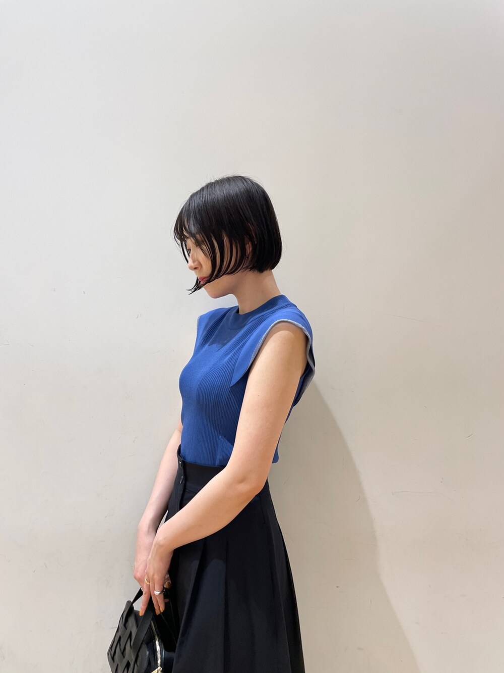 ブルー系のスカート、ブルー系のニット/セーター、ブラック系のショルダーバッグを着用したレディースの夏コーディネートの7枚目の写真