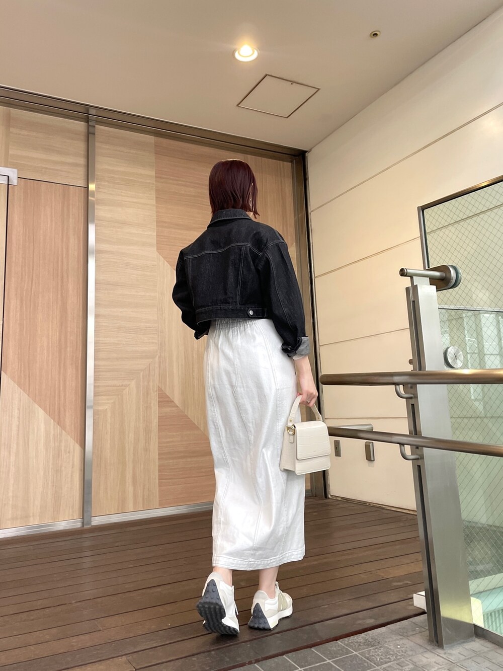 ホワイト系のショルダーバッグ、ホワイト系のワンピース、ブラック系のデニムジャケットを着用したレディースの春コーディネートの6枚目の写真