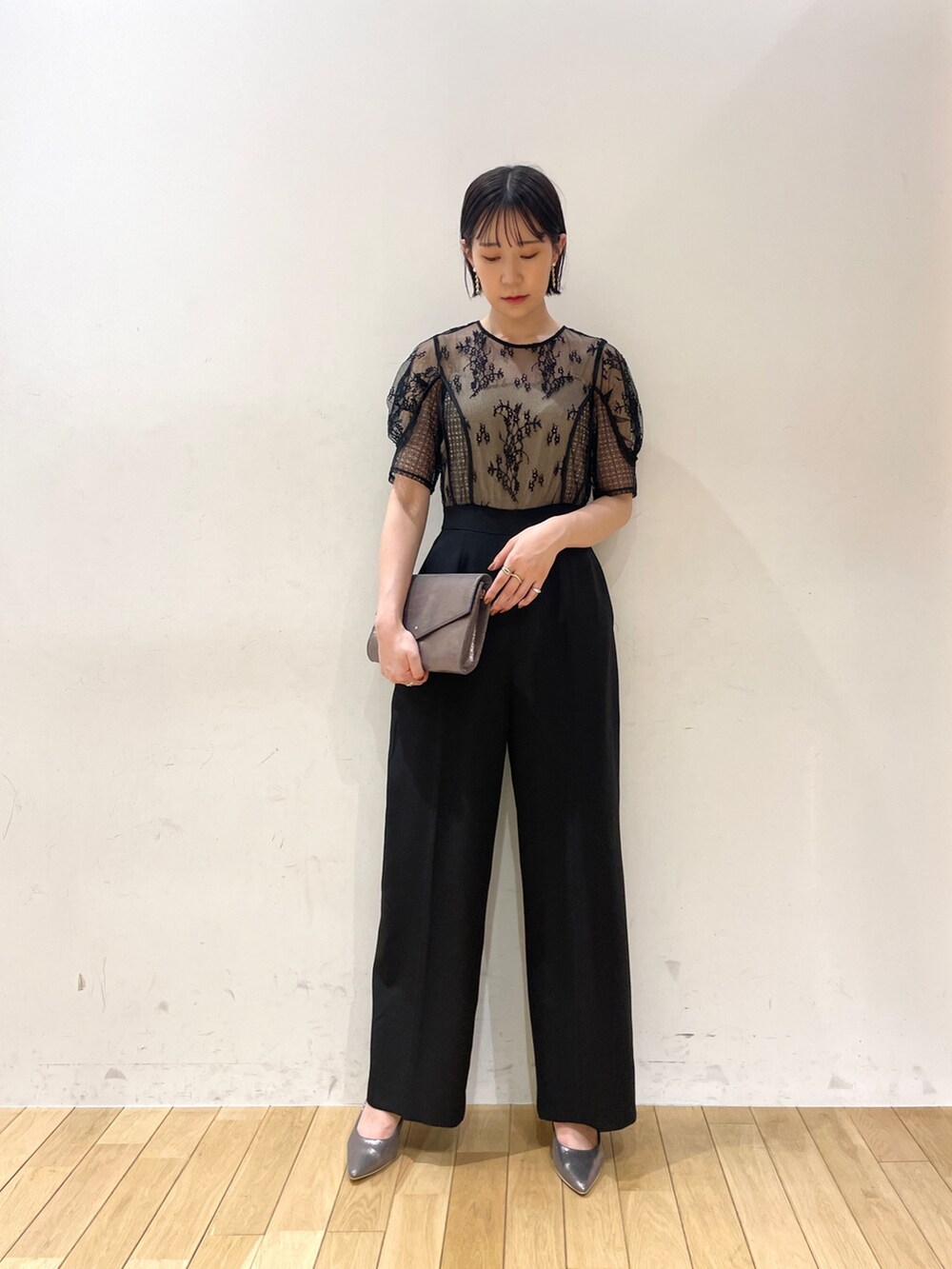 シルバー系のハンドバッグ、シルバー系のパンプス、ブラック系のパンツドレスを着用したレディースの夏コーディネートの2枚目の写真