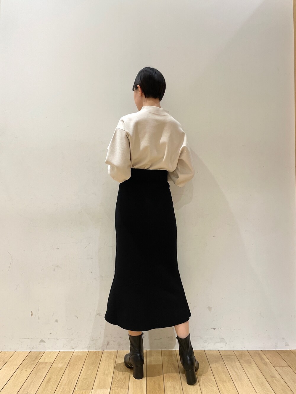 ブラック系のスカート、ホワイト系のニット/セーター、ブラック系のブーツを着用したレディースの冬コーディネートの6枚目の写真