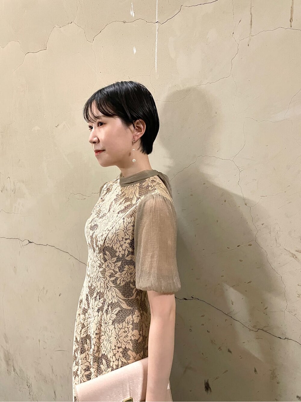 ベージュ系のドレス、ゴールド系のパンプス、ベージュ系のクラッチバッグを着用したレディースの秋コーディネートの6枚目の写真