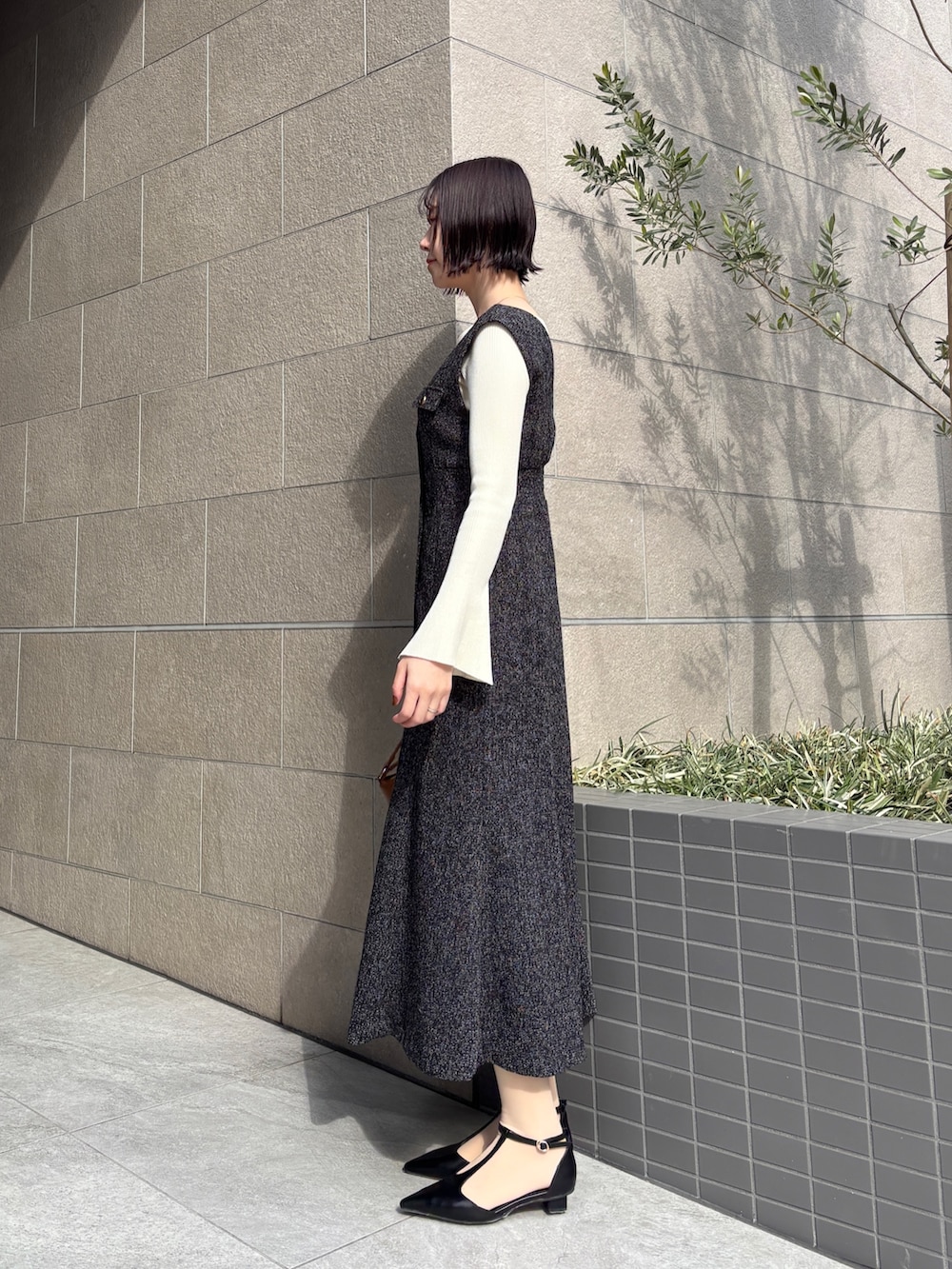 ブラック系のワンピース、ホワイト系のニット/セーター、イエロー系のハンドバッグを着用したレディースの冬コーディネートの2枚目の写真