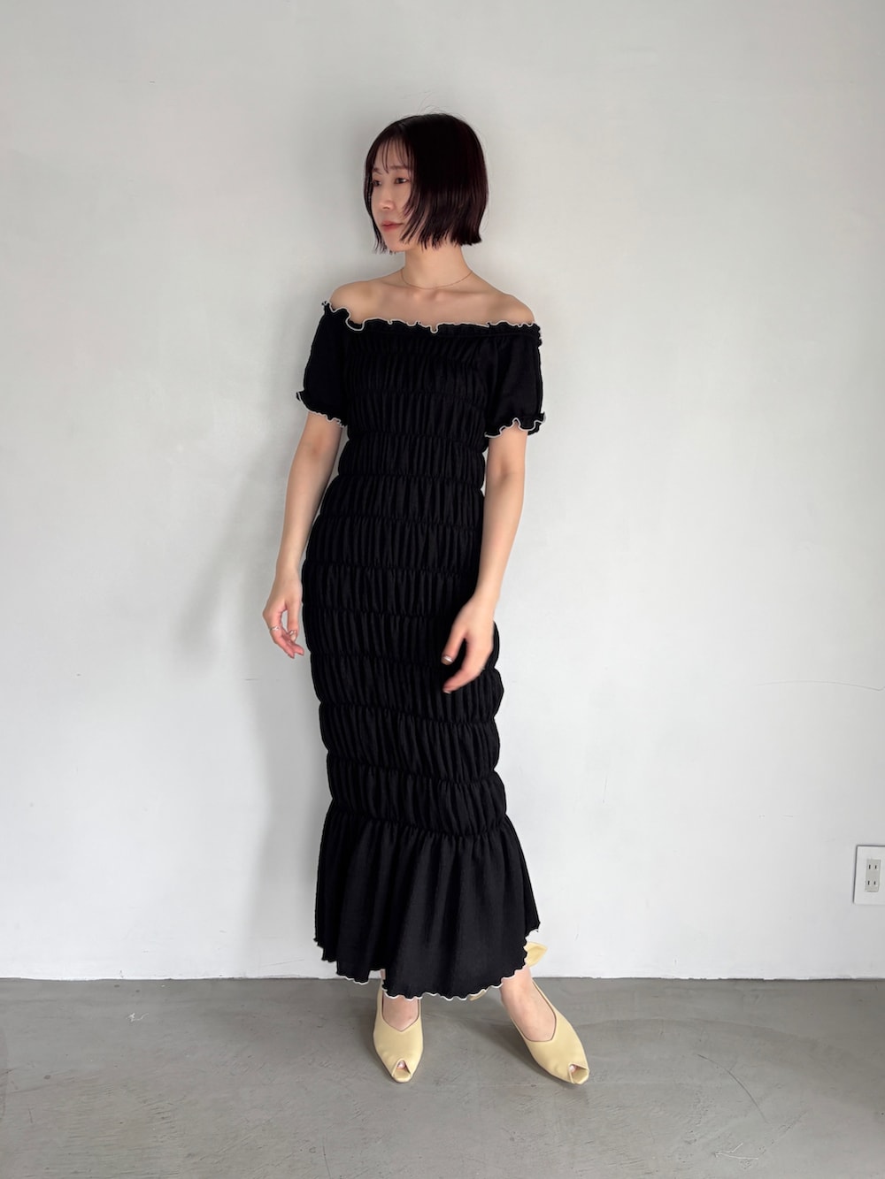 ブラック系のワンピース、イエロー系のパンプスを着用したレディースの夏コーディネートの2枚目の写真