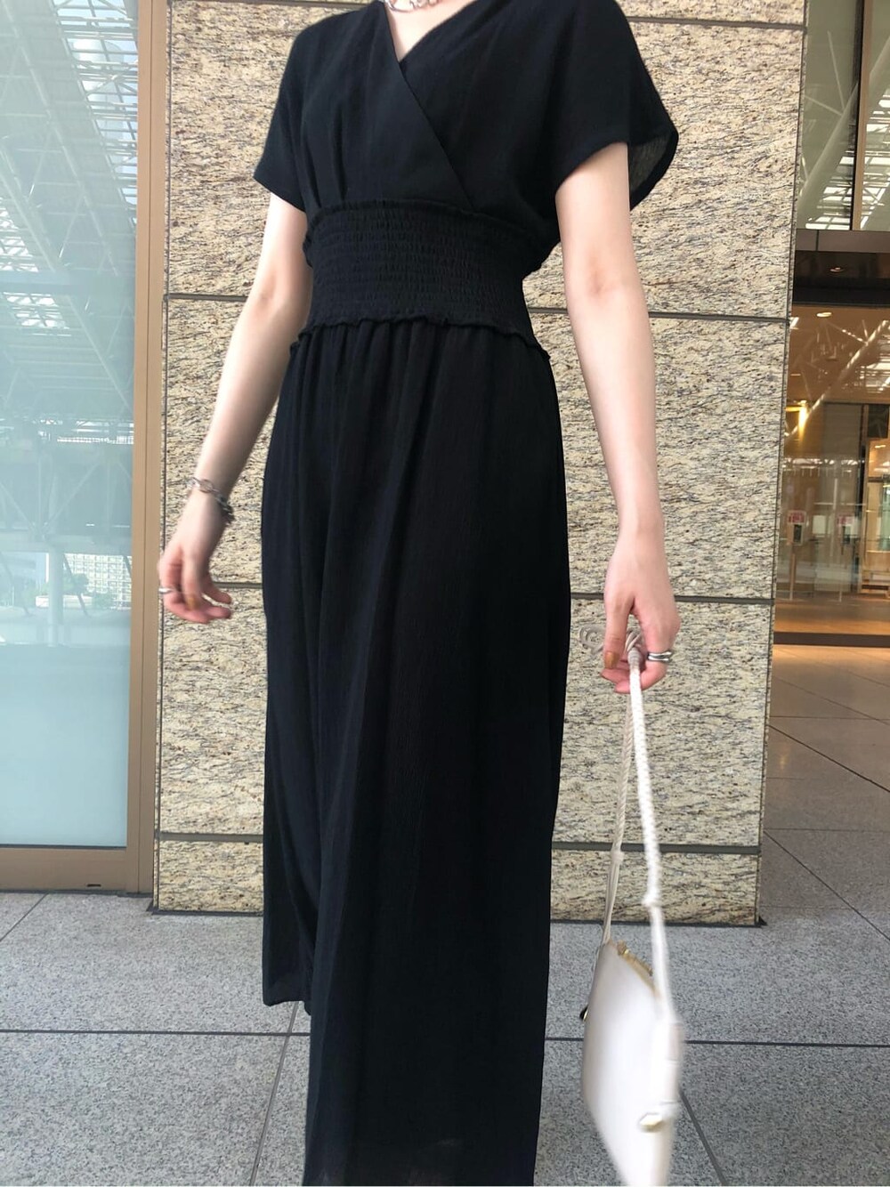 ブラック系のワンピース、ブラウン系のサンダル、シルバー系のブレスレットを着用したレディースの夏コーディネートの3枚目の写真