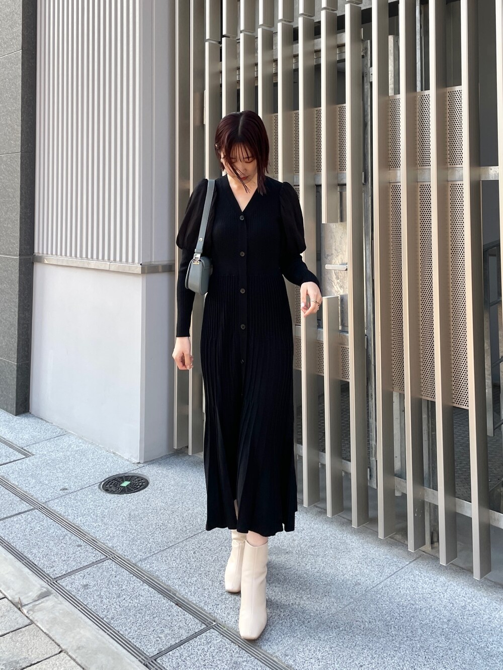 ブラック系のワンピース、ブルー系のショルダーバッグ、ホワイト系のブーツを着用したレディースの冬コーディネートの2枚目の写真