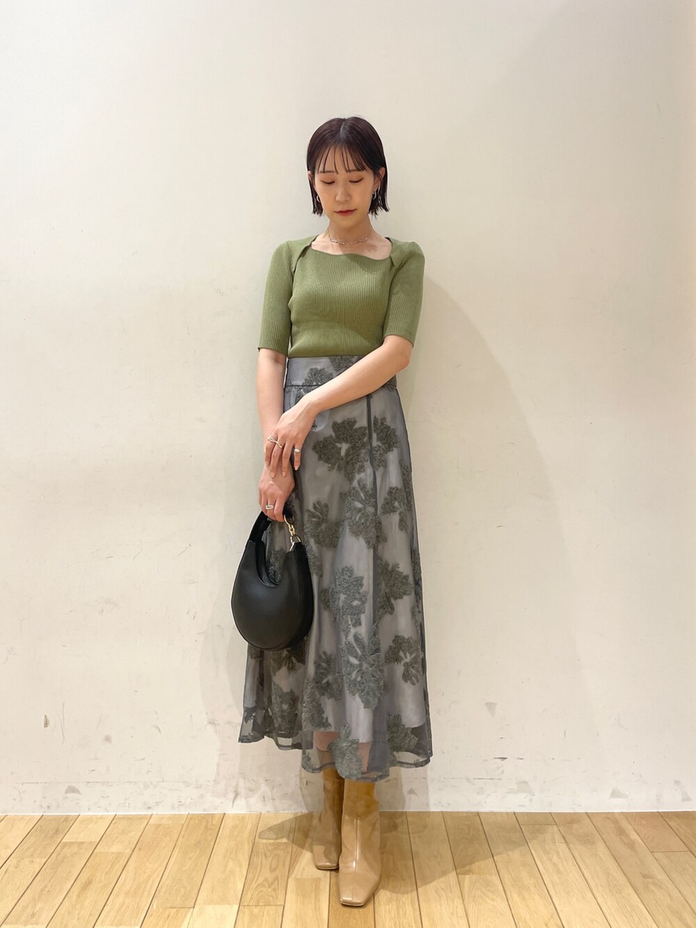 ベージュ系のブーツ、グリーン系のニット/セーター、グレー系のスカートを着用したレディースの夏コーディネートの2枚目の写真