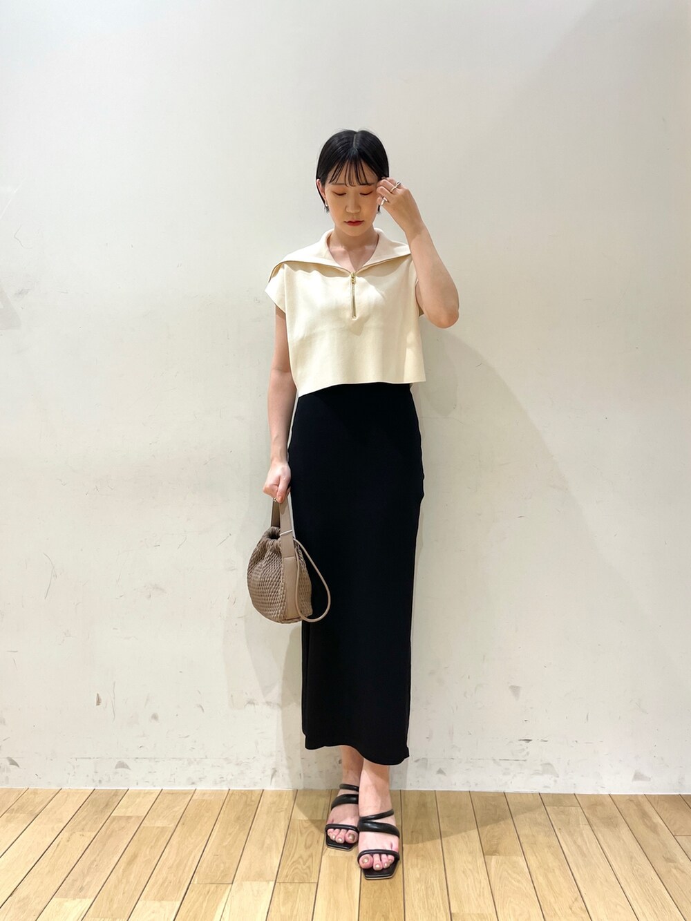 ブラック系のスカート、ホワイト系のニット/セーター、ブラウン系のハンドバッグを着用したレディースの春コーディネートの3枚目の写真