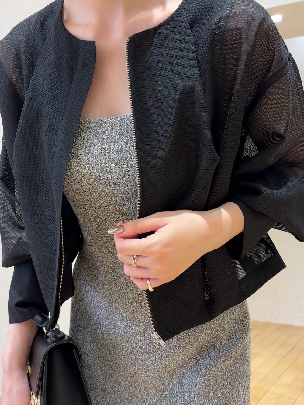 グレー系のワンピース、ブラック系のブルゾン、ブラック系のハンドバッグを着用したレディースの春コーディネートの4枚目の写真