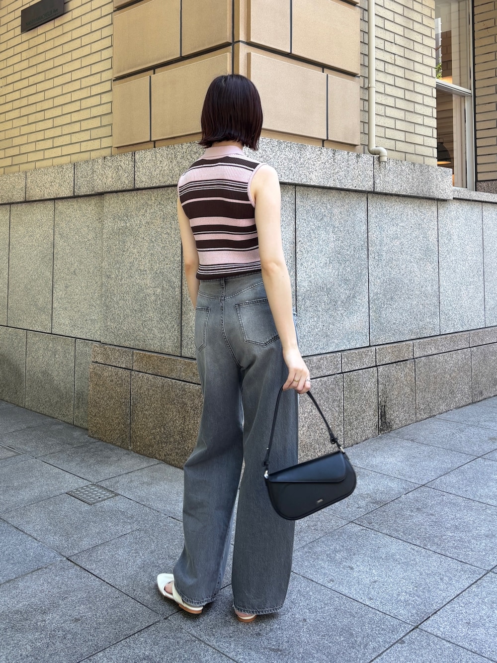 グレー系のデニムパンツ、ピンク系のニット/セーター、ホワイト系のサンダルを着用したレディースの春コーディネートの2枚目の写真