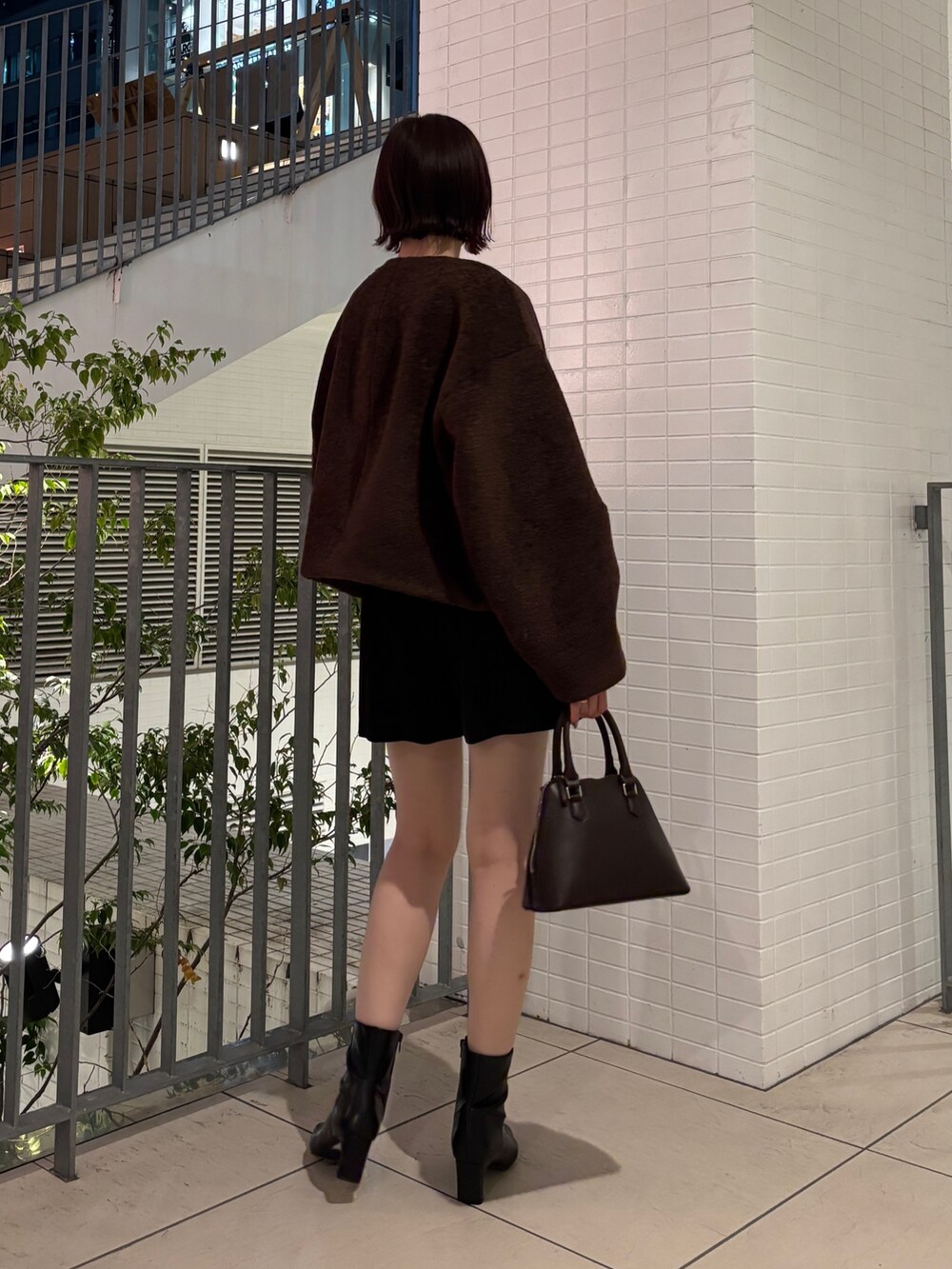 グレー系のニット/セーター、ブラウン系のブルゾン、ブラウン系のボストンバッグを着用したレディースの秋コーディネートの3枚目の写真