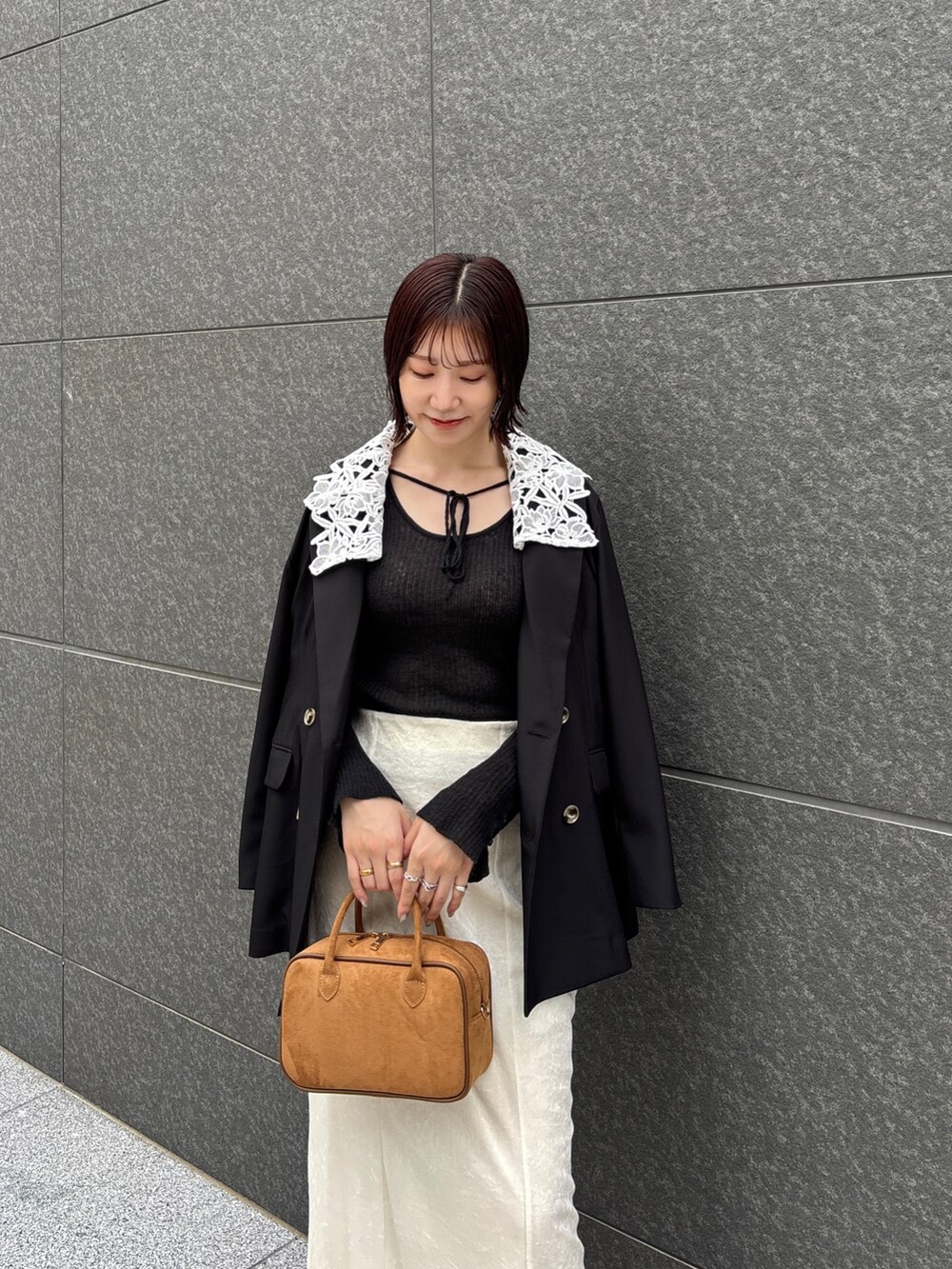 ホワイト系のスカート、イエロー系のハンドバッグ、ブラック系のブーツを着用したレディースの秋コーディネートの2枚目の写真